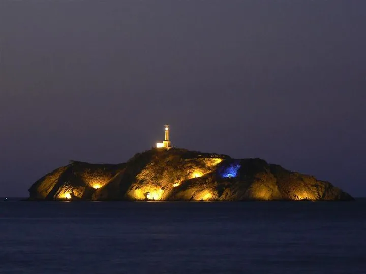 Faro iluminado en isla, obra de señalización marítima